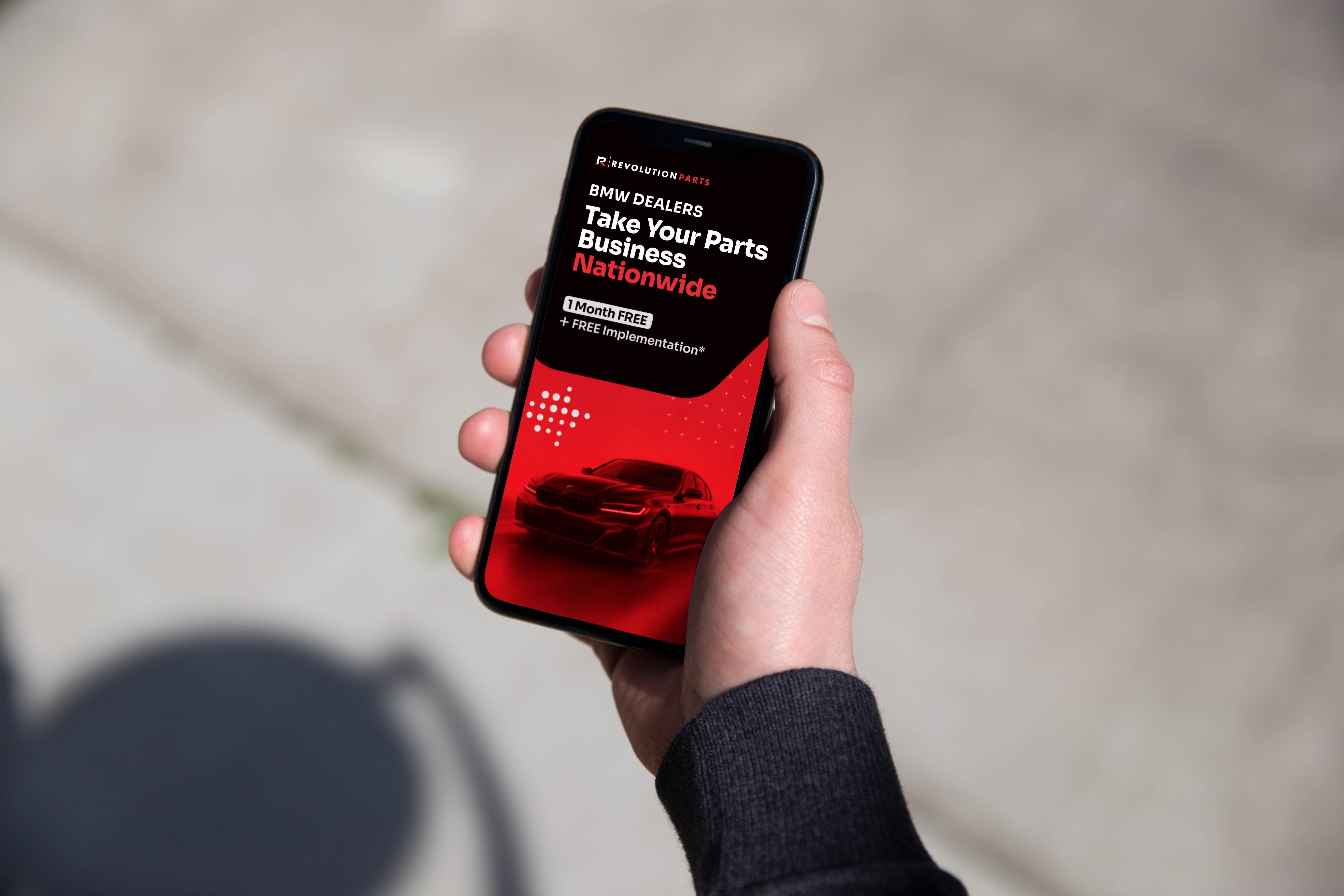 Hand holding a phone displaying the BMW Dealers Nationwide promotional ad