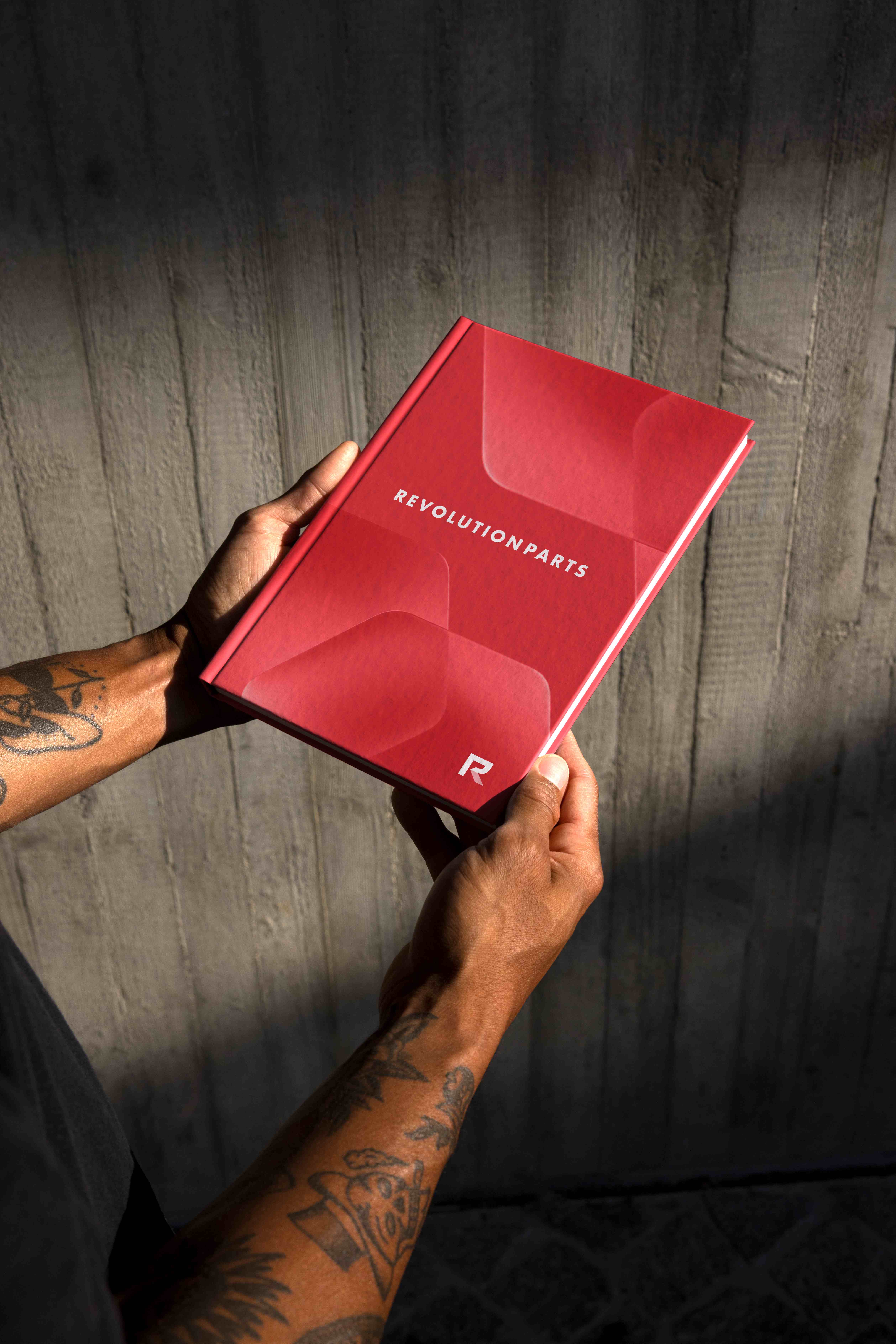 Hands holding a red hardcover RevolutionParts brand book
